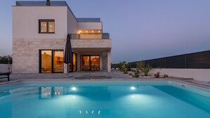 Una casa moderna de dos pisos con piscina, ventanas amplias y un espacio de patio.