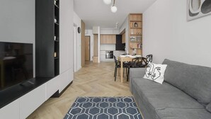 Una sala de estar moderna con un sofá gris, una mesa de comedor y una cocina al fondo.