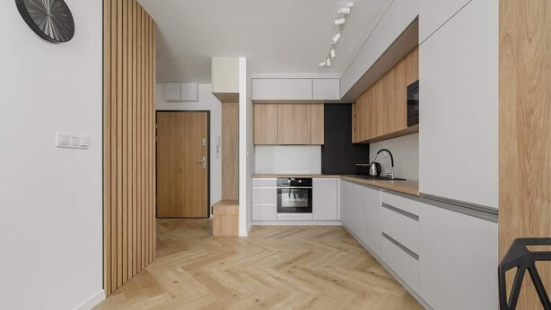 Una cocina moderna con armarios de madera, horno empotrado y suelo con estampado de espiga.