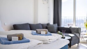 Camera d'albergo con due letti, un divano, un tavolino e un balcone con vista.