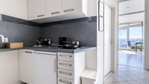 Una cucina moderna con mobili bianchi, un piano di lavoro nero e vista sul balcone.