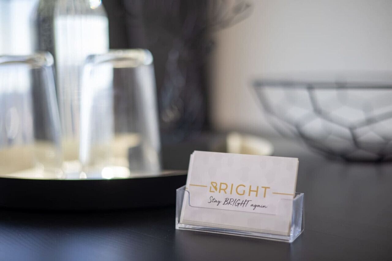 A business card holder with the text "BRIGHT Stay BRIGHT again" on a table.