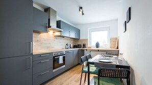 A modern kitchen with grey cabinets, a wooden countertop, and a dining area with a table and chairs.