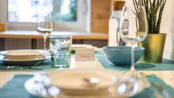 Une table dressée avec un verre transparent, une assiette blanche, un bol bleu, une petite carte, une bouteille et une plante en pot.