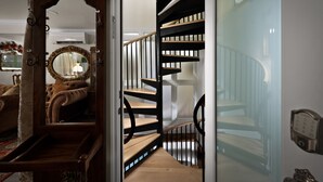 A staircase with wooden steps and black railings, leading to a landing with a mirror and a lamp. - The French Farmhouse at Midtown Manor - Hot Tub! (Bend)