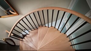 A spiral staircase with wooden steps and black balusters. - The French Farmhouse at Midtown Manor - Hot Tub! (Bend)