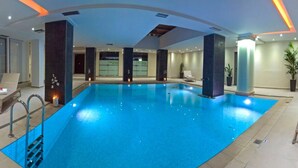 Un'ampia piscina interna con sedie a sdraio e un'area idromassaggio.