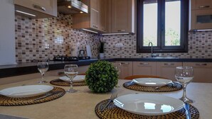 Une cuisine avec un mur recouvert de carreaux, une fenêtre et une table à manger mise avec des assiettes, des couverts et des verres.