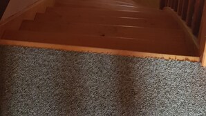 A wooden staircase with a carpeted landing, a small window, and a wall-mounted decorative piece. - Country house in Livradois Forez (Saint-Victor-Montvianeix)
