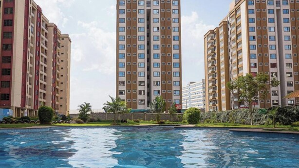 Un ensemble immobilier résidentiel comprenant plusieurs immeubles à étages, une piscine et des espaces verts aménagés.