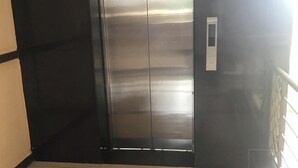 Une porte d’ascenseur en métal, avec un panneau de commande fixé au mur.