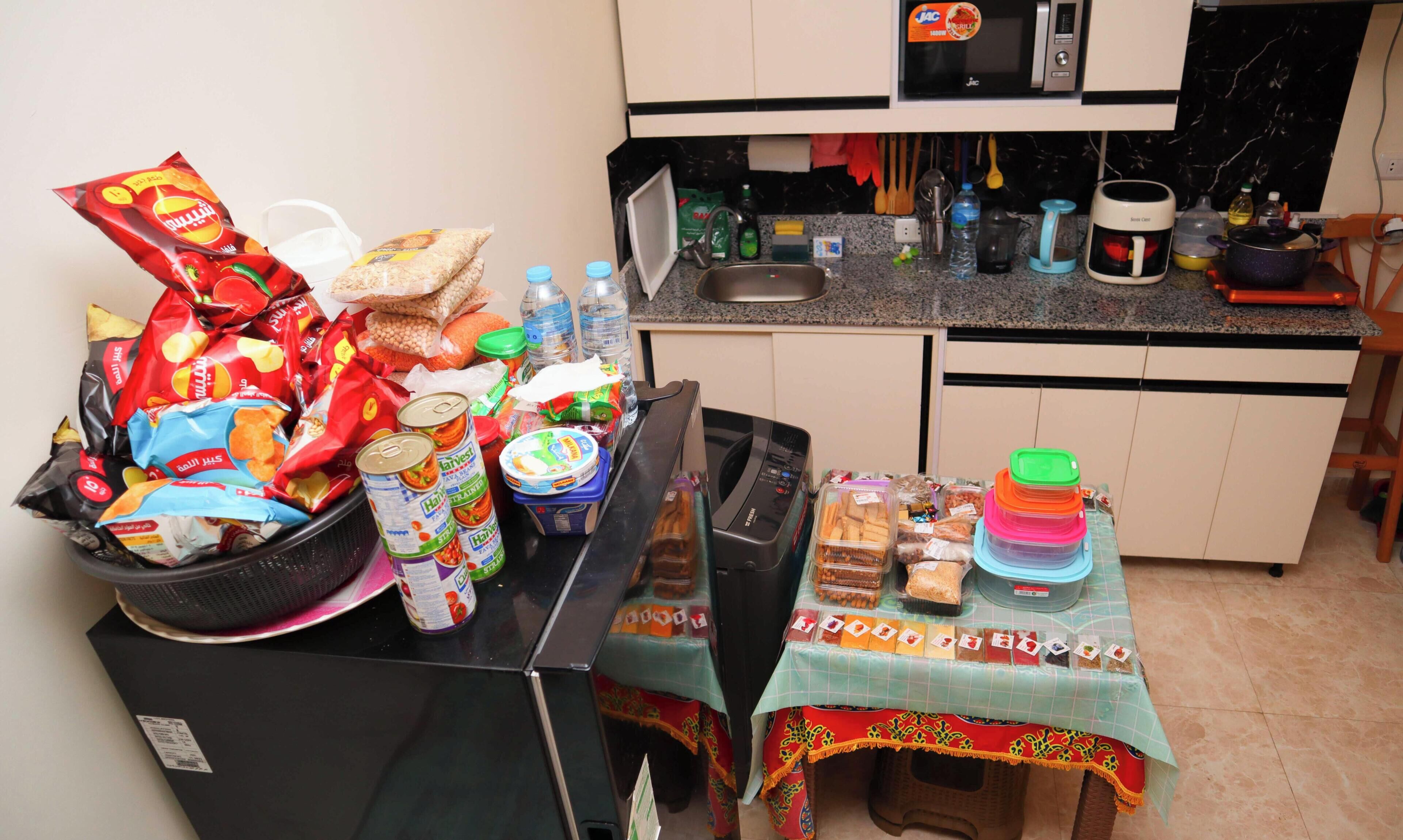 A kitchen with a microwave, sink, and various food items and containers.