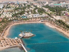 An aerial view of a coastal resort with a central island, a beach, and a marina.