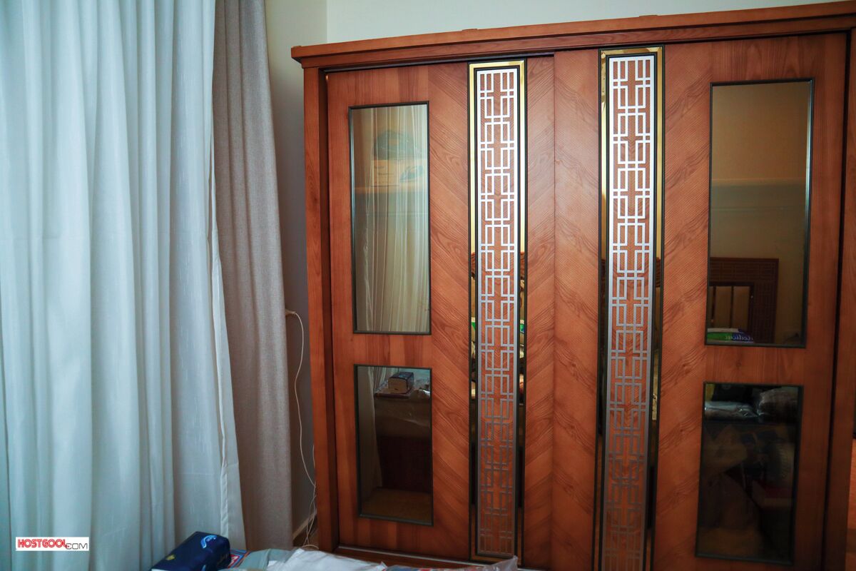 A wooden wardrobe with mirrored doors and a decorative panel.