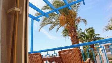 A balcony with wicker chairs, a palm tree, and a blue railing.