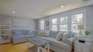 A modern living room with two grey sofas, a wooden coffee table, and a white side table with a lamp. - Beachy 3 bedroom home with central air, just .5 miles to the beach (Dennis Port)