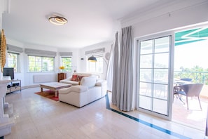 A spacious living room with a sofa, coffee table, and a dining area with chairs and a table.