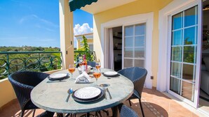 A round table with chairs, a bottle of wine, and glasses on a balcony with a view. - 42 Presa do Moura, beautiful townhouse on stunning complex with pool and gym! (Carvoeiro)