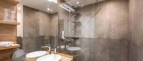 Un baño moderno con dos lavamanos, una ducha y cabina de ducha de vidrio.