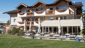 Un hotel de varios pisos con terraza al aire libre y un césped cuidado.