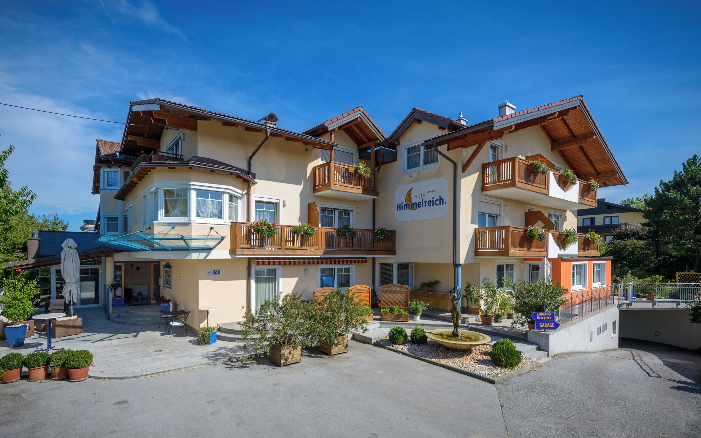 A multi-story hotel with balconies, a reception area, and a parking garage.