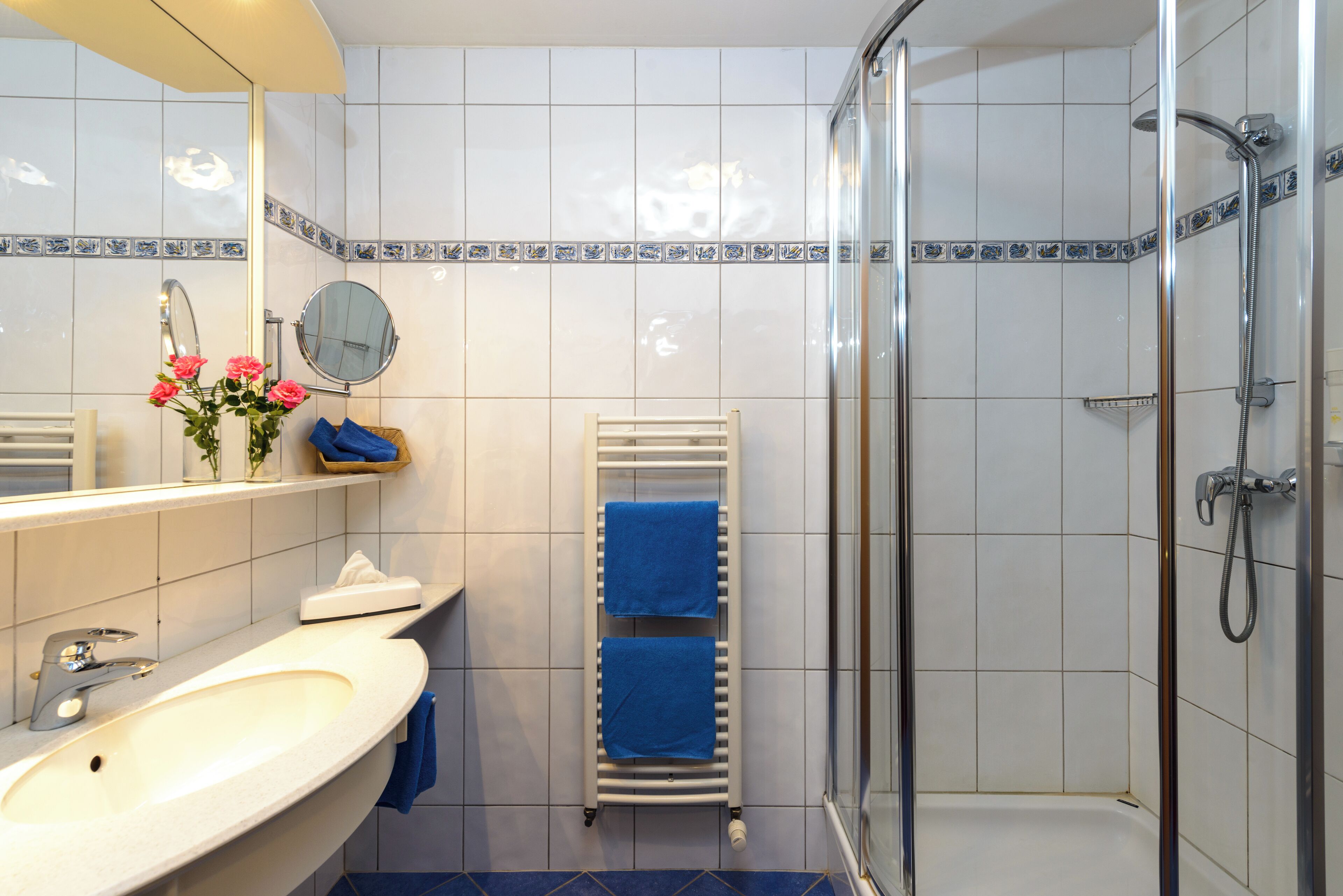 A bathroom with a sink, mirror, and shower.