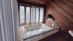 Un bagno moderno con una vasca freestanding, pareti in legno e una finestra con persiane verticali.