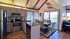 Una cucina moderna con elettrodomestici in acciaio inossidabile, un'isola centrale e un'area pranzo con vista all'esterno.
