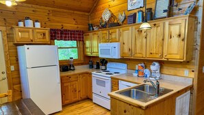 Eine Holzhüttenküche mit Kühlschrank, Mikrowelle, Herd und Spüle.