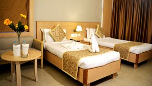 A hotel room with two beds, a round table with a vase of flowers, and a sofa.