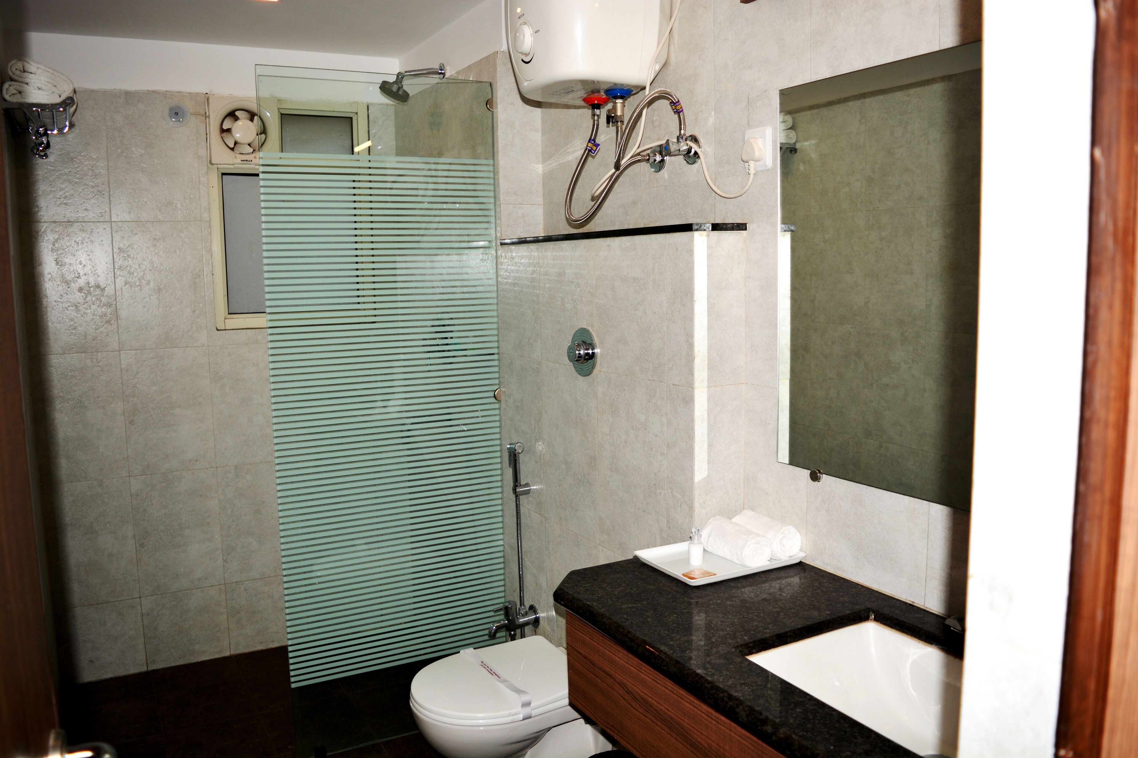 A bathroom with a toilet, sink, mirror, and shower.