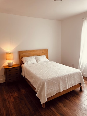 Een slaapkamer met een houten bed, een bedlampje en een nachtkastje.