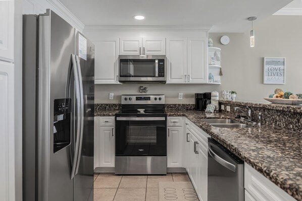 A modern kitchen with stainless steel appliances, granite countertops, and white cabinetry. - Your Private Balcony Overlooking the Area's Largest Private Beach Awaits (Panama City Beach)