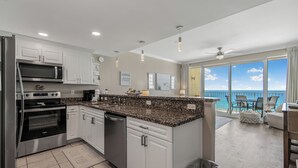 A modern kitchen with stainless steel appliances, a granite countertop, and a view to the balcony.