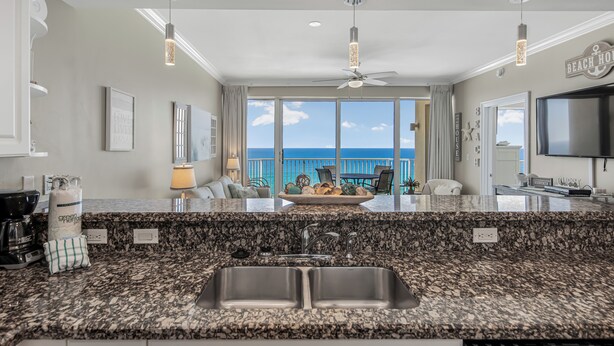 A kitchen with granite countertops, a double sink, and a view of the ocean.