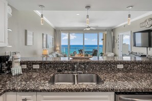 A kitchen with granite countertops, a double sink, and a view of the ocean. - Your Private Balcony Overlooking the Area's Largest Private Beach Awaits (Panama City Beach)