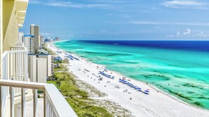 A beach with white sand, clear turquoise water, and a row of blue umbrellas. - Upgrade to a Getaway! (Panama City Beach)