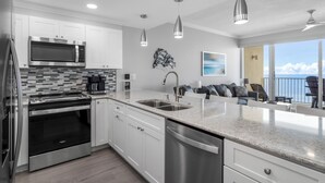 A modern kitchen with stainless steel appliances, white cabinetry, and a large island with a sink.