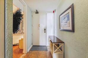 Un pasillo con una puerta, un cuadro en la pared y un pequeño banco de madera.