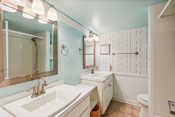Un baño con dos lavamanos, una ducha y un inodoro.