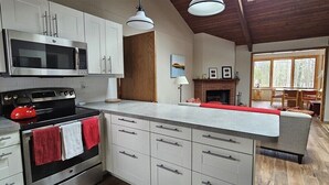 Eine moderne Küche mit Edelstahlgeräten, einem Kamin und einem Essbereich mit Tageslicht.
