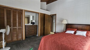 Ein Schlafzimmer mit Bett, Holzschrank, Nachttisch und Spiegel.