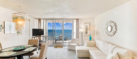 A hotel room with a balcony, a dining area, and a living room.
