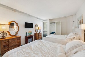 A hotel room with two beds, a TV, a wardrobe, and a mirror.