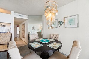 Un comedor con una mesa redonda, sillas acolchadas y una lámpara colgante decorativa.