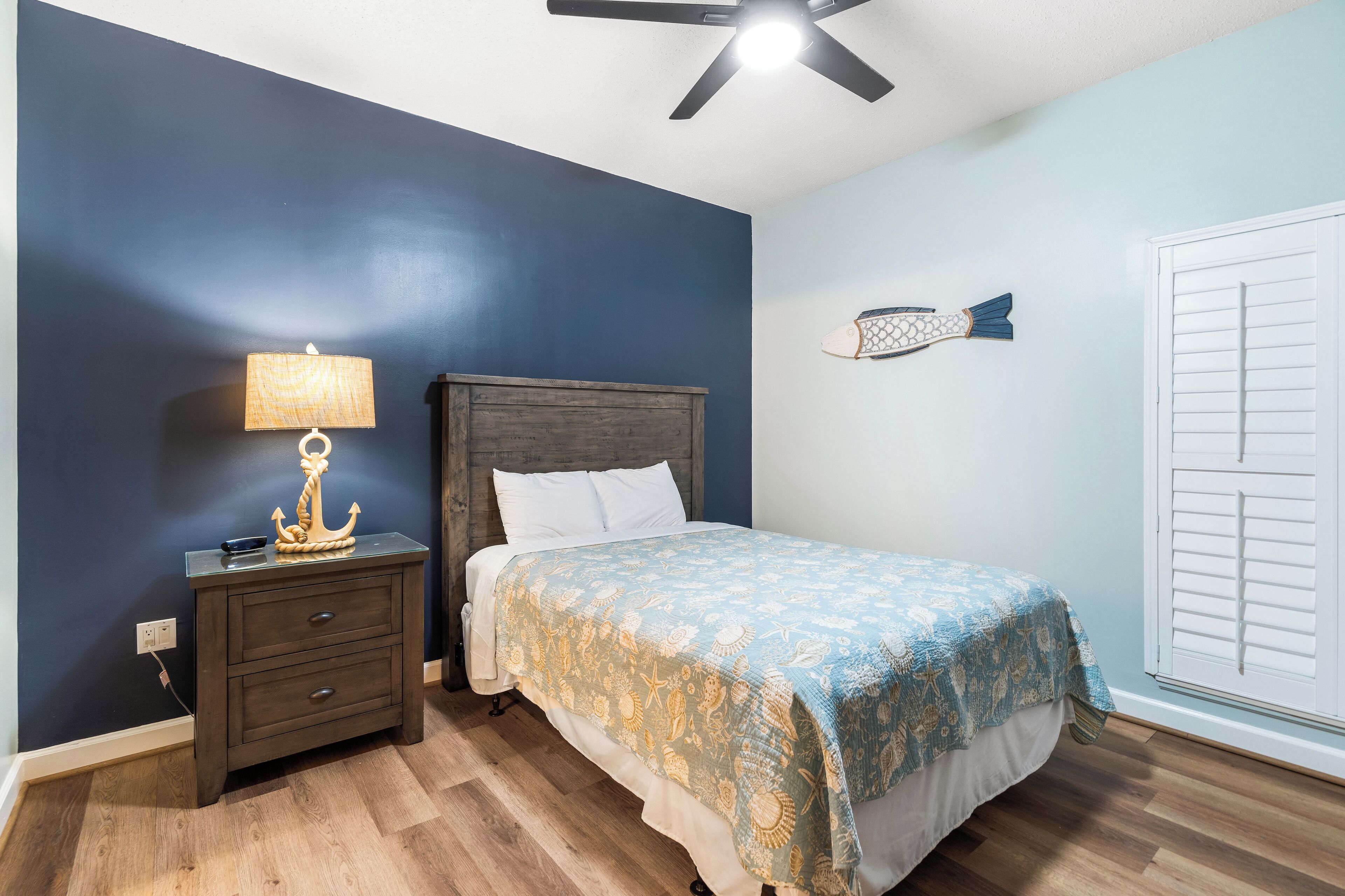 A bedroom with a bed, a nightstand, a lamp, and a ceiling fan.