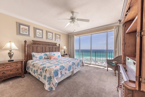 A bedroom with a large bed, a ceiling fan, and a view of the ocean. - This Beachfront Beauty is Waiting for You! (Panama City Beach)