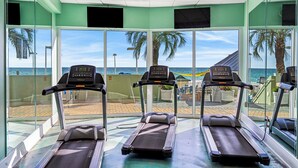 A fitness area with treadmills and a view of the beach.