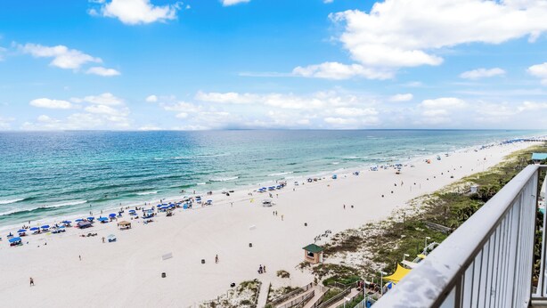A beach with umbrellas and people, a clear sky, and a view of the ocean. - Updated Condo on Miles of Beach! (Panama City Beach)