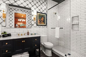 A modern bathroom with a black vanity, white subway tiles, a framed Vanity poster, and a glass shower enclosure.